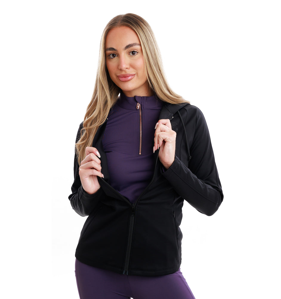 
                  
                    Woman wearing a black jacket over a purple top and leggings on a white background
                  
                