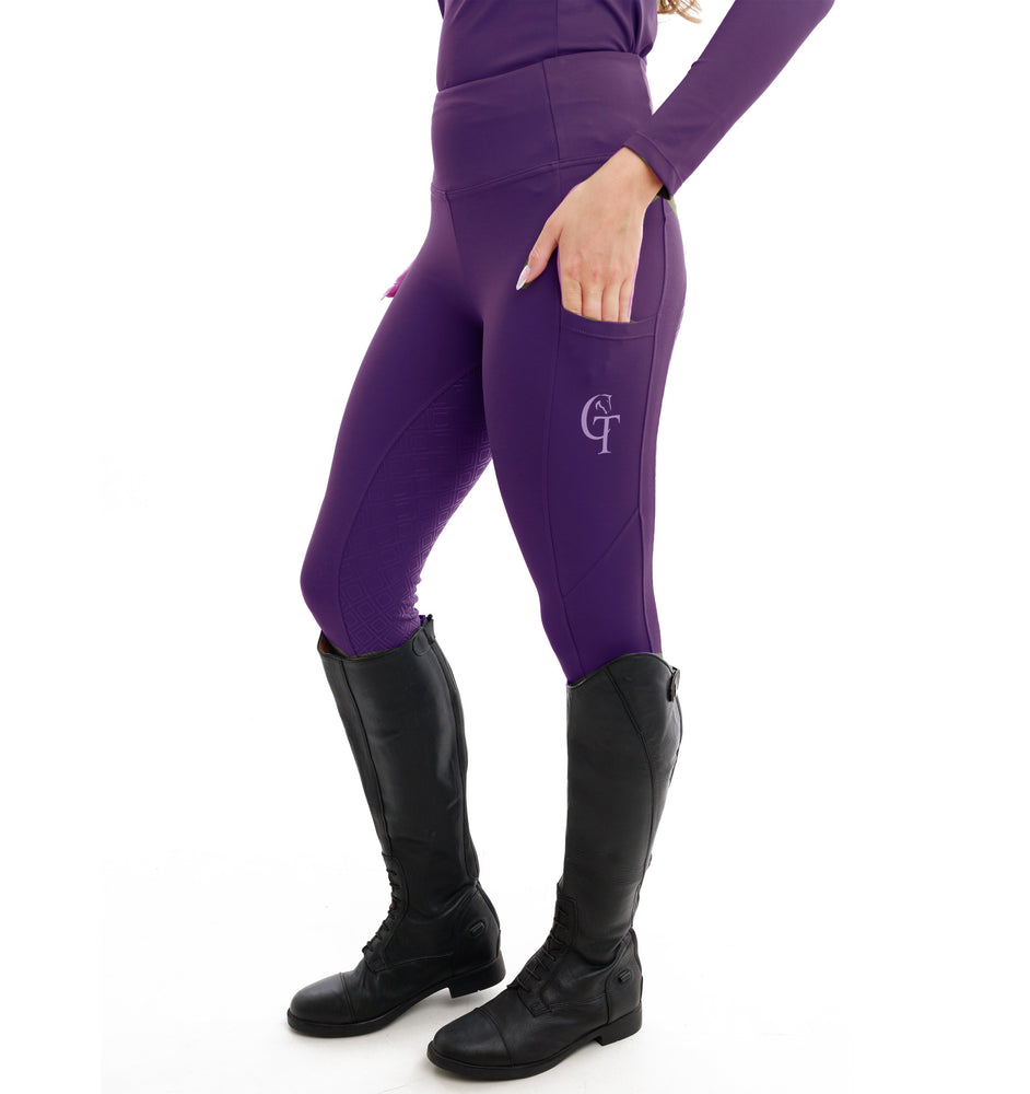 Person wearing purple riding pants with a logo and black riding boots on a white background