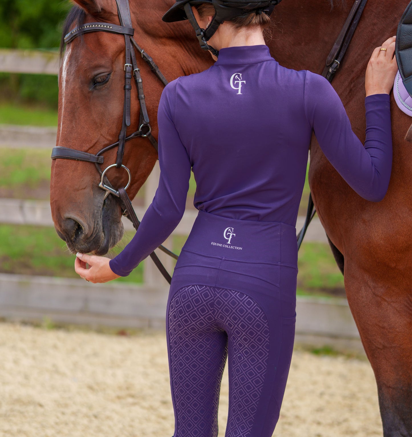 
                  
                    Person wearing a purple equestrian outfit with a horse in an outdoor setting
                  
                