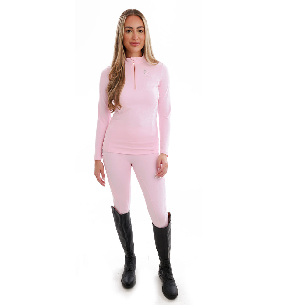 
                  
                    Woman wearing a pink long-sleeve top and trousers with black knee high riding boots on a white background
                  
                