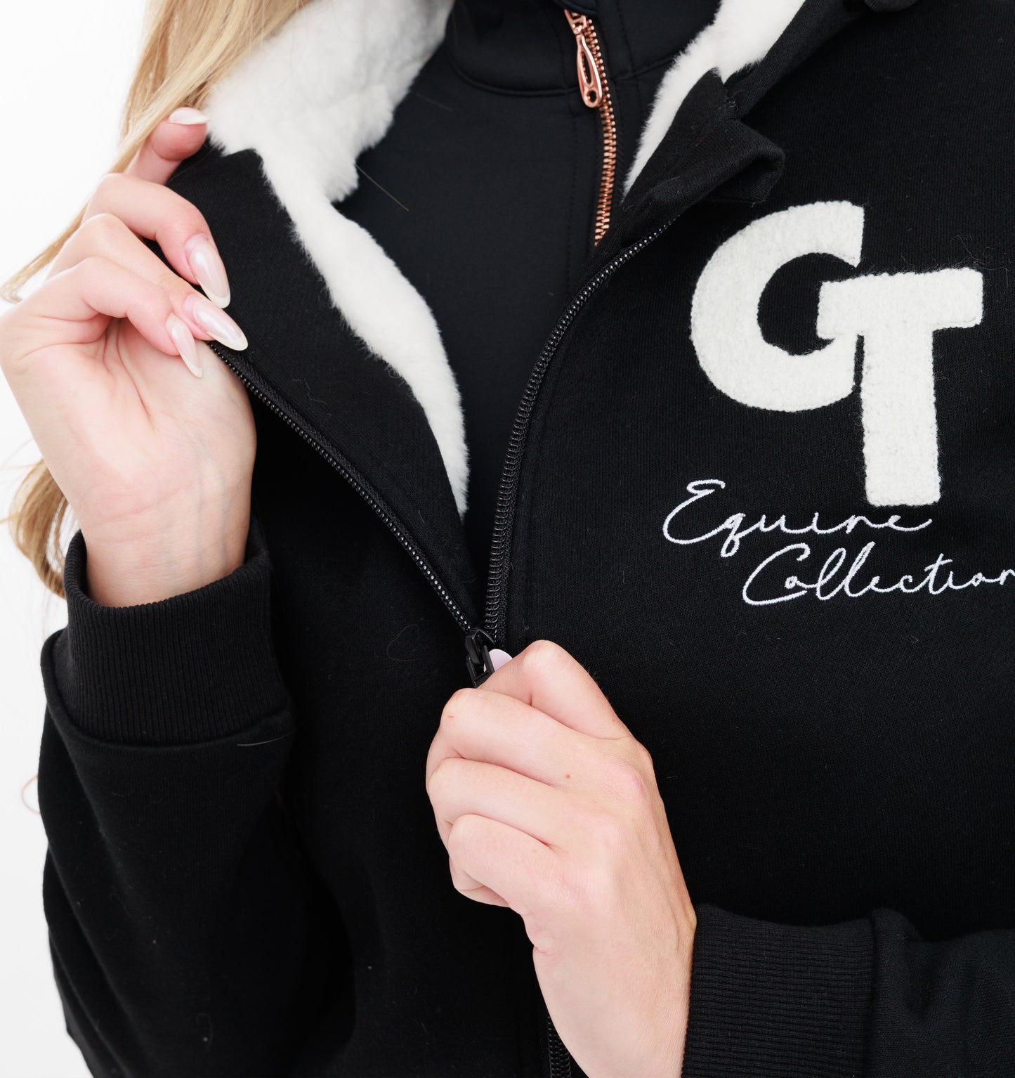 
                  
                    Black jacket with white fur lining and 'GT Equine Collection' logo
                  
                