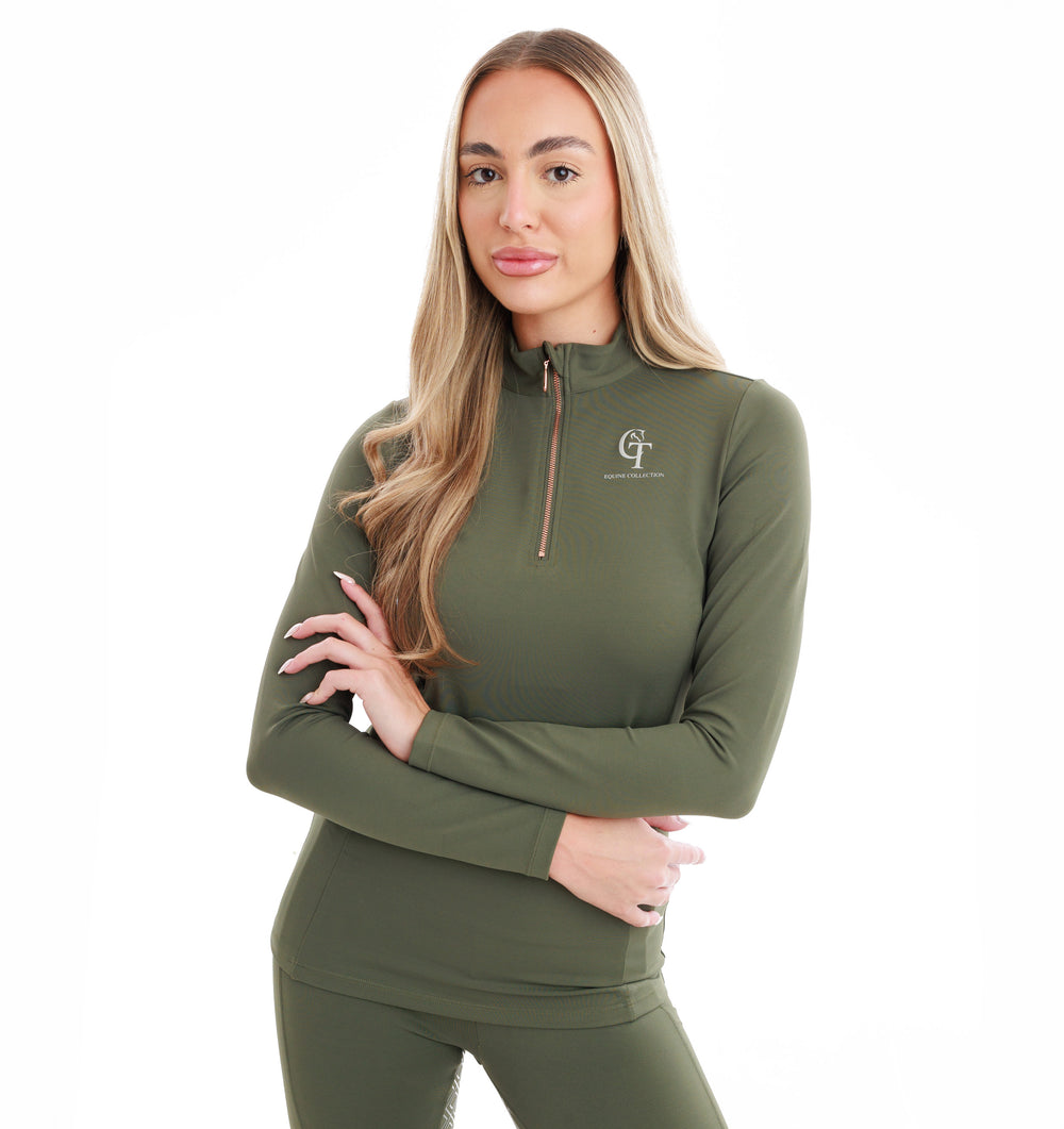 Woman with arms folded wearing an olive green athletic outfit with a logo on a white background