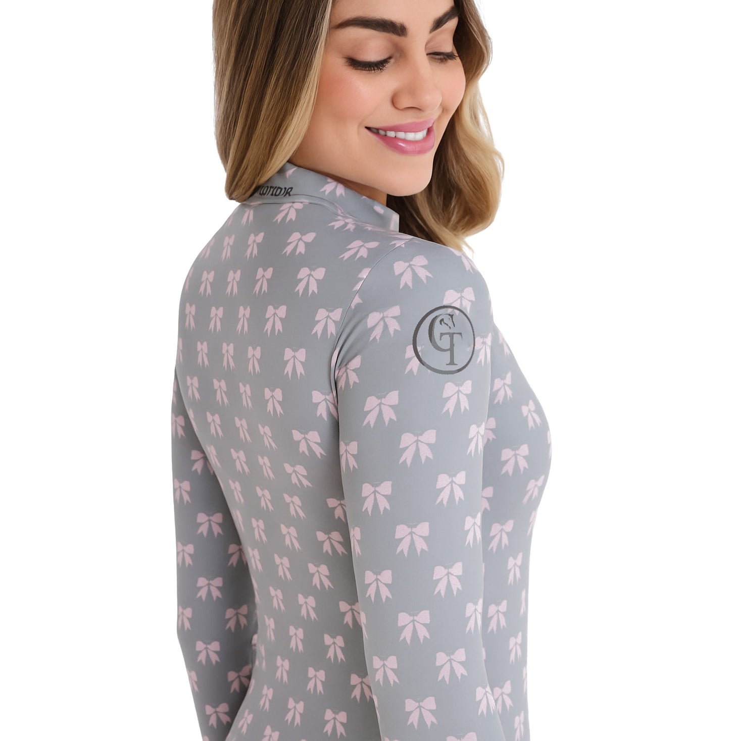 
                  
                    Woman wearing a grey long-sleeve shirt with pink bow pattern on a white background
                  
                