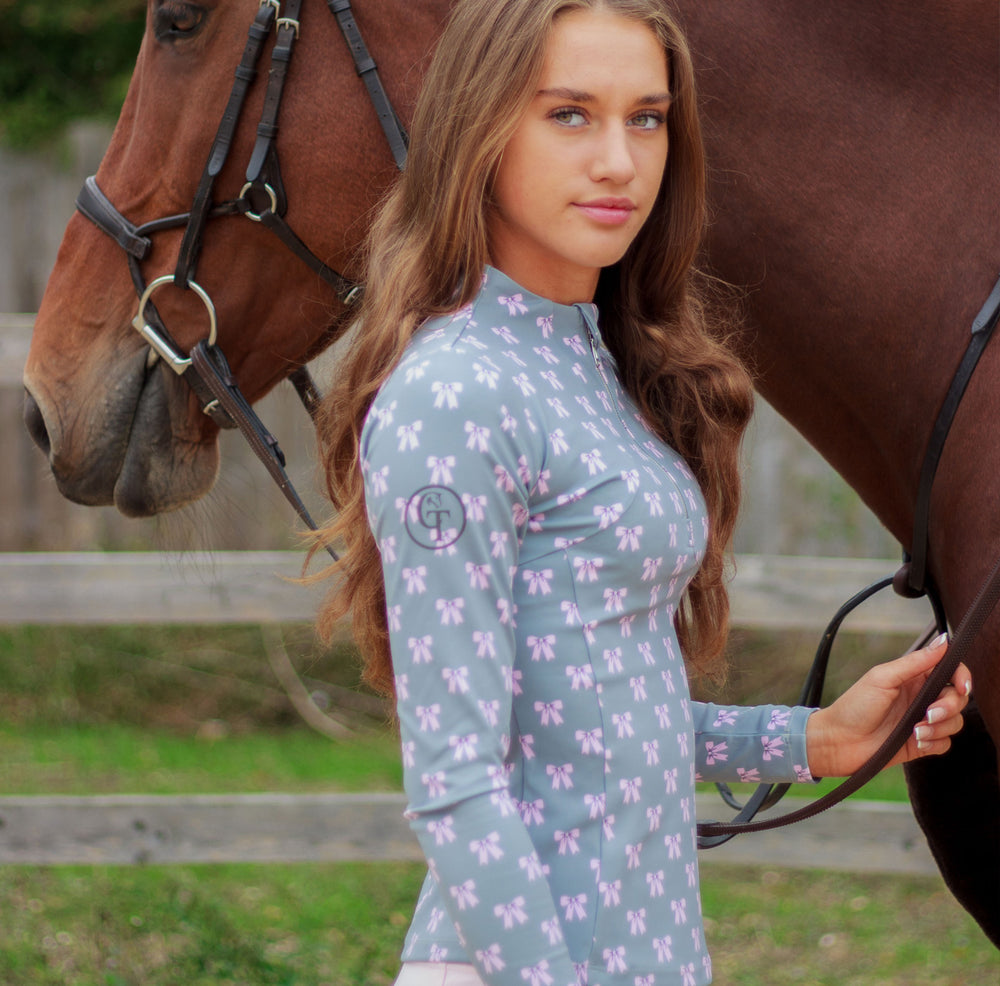 
                  
                    Woman in a patterned shirt standing next to a horse in an outdoor setting
                  
                